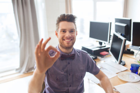 business, startup, gesture and people concept - happy businessman or creative male office worker with computers showing ok hand sign